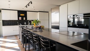 Une cuisine moderne dotée d’un îlot central, d’appareils électroménagers en acier inoxydable et d’une palette de couleurs en noir et blanc.