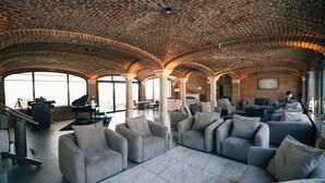Un salon spacieux doté d’un haut plafond voûté en briques et de grandes fenêtres.
