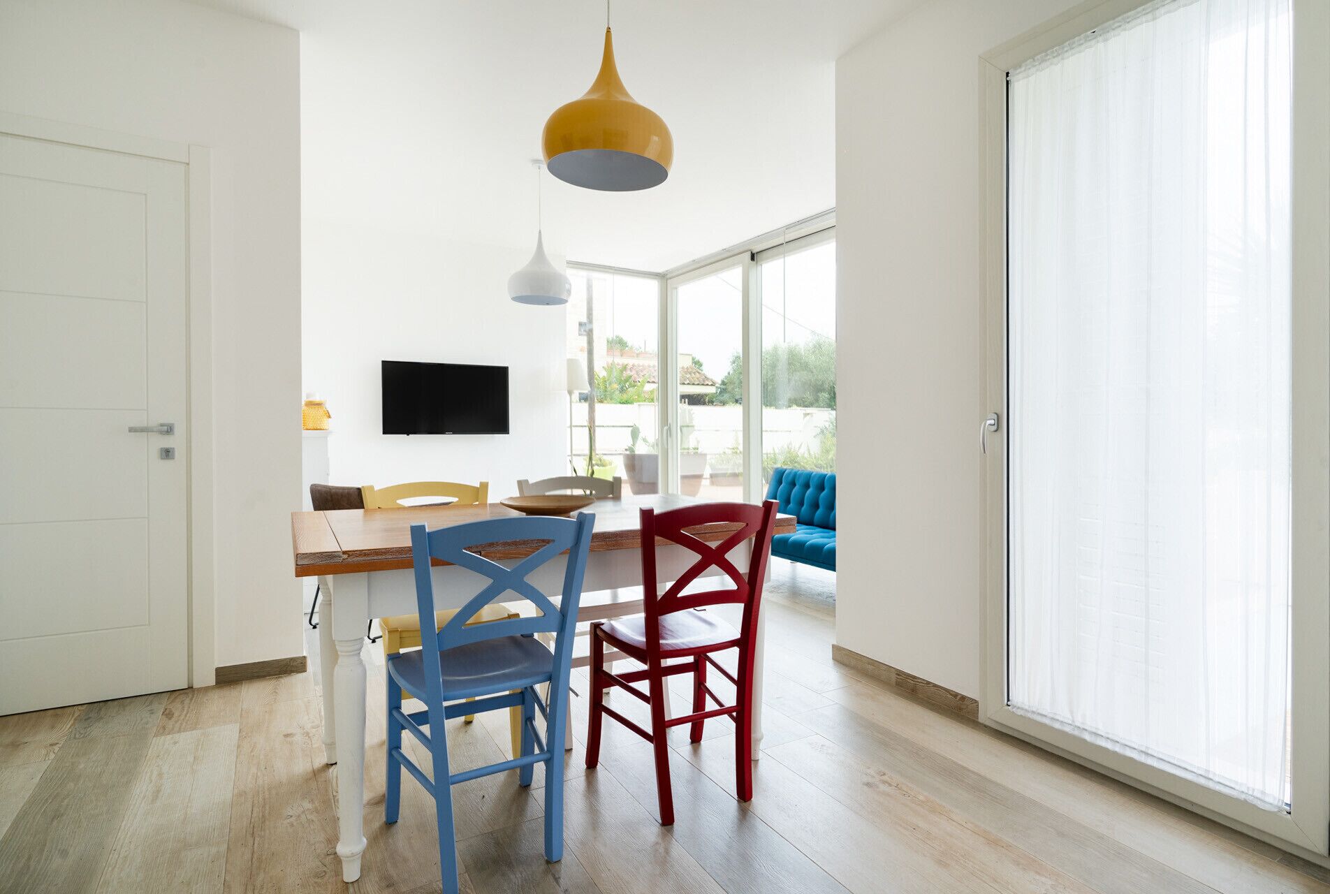 A modern dining area with a wooden table, two chairs, and a television mounted on the wall.