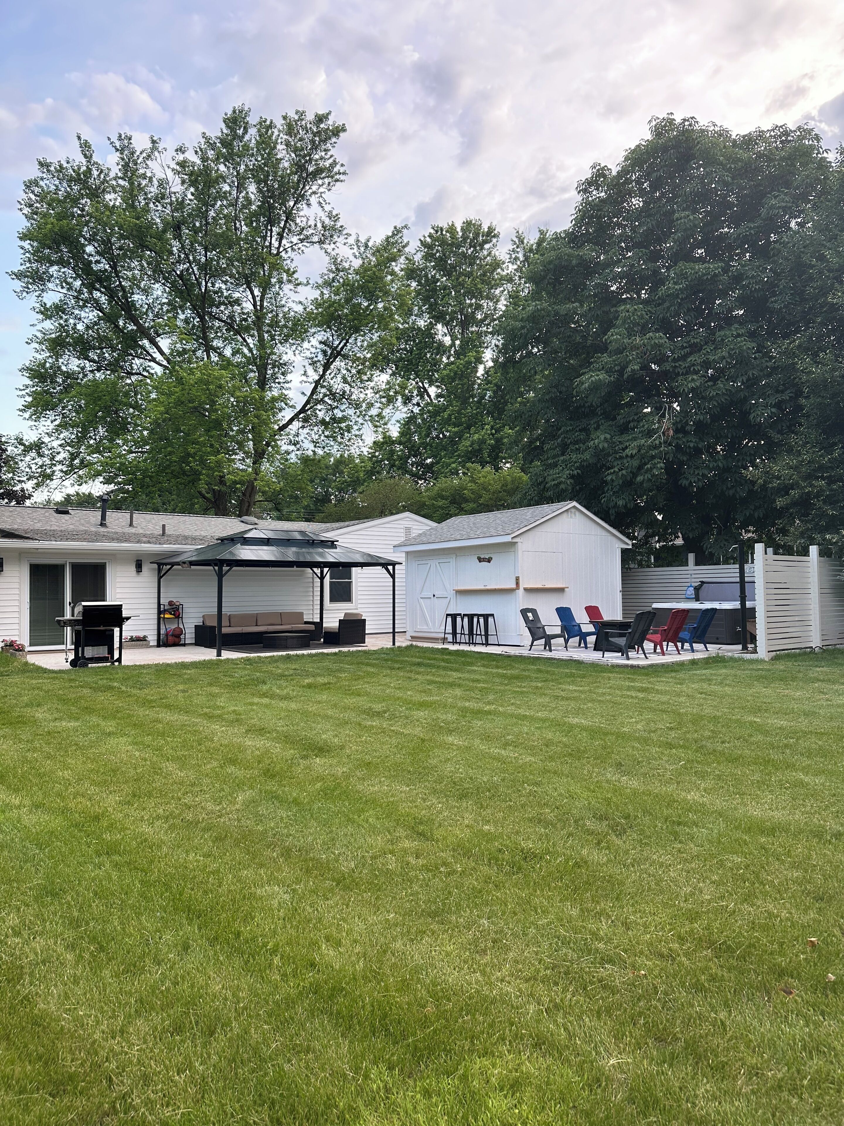 A backyard with a covered patio, a barbecue grill, and outdoor seating.
