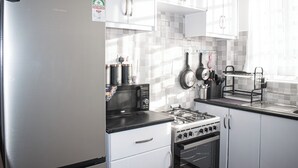 Une cuisine moderne dotée d’appareils électroménagers en acier inoxydable, de meubles blancs et d’une fenêtre laissant entrer la lumière naturelle.