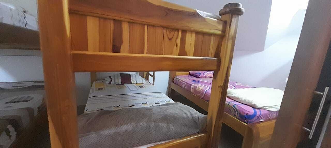 Ein Etagenbett mit Holzgestell und einer grauen Matratze auf der unteren Koje.