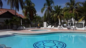 A swimming pool with a blue geometric design, surrounded by palm trees and lounge chairs. - Cabaña de Enseño en Coveñas (Coveñas)