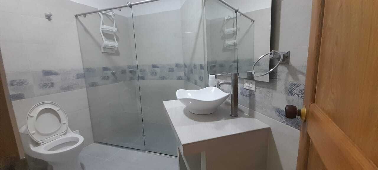 A modern bathroom with a glass-enclosed shower, a white sink, and a toilet.