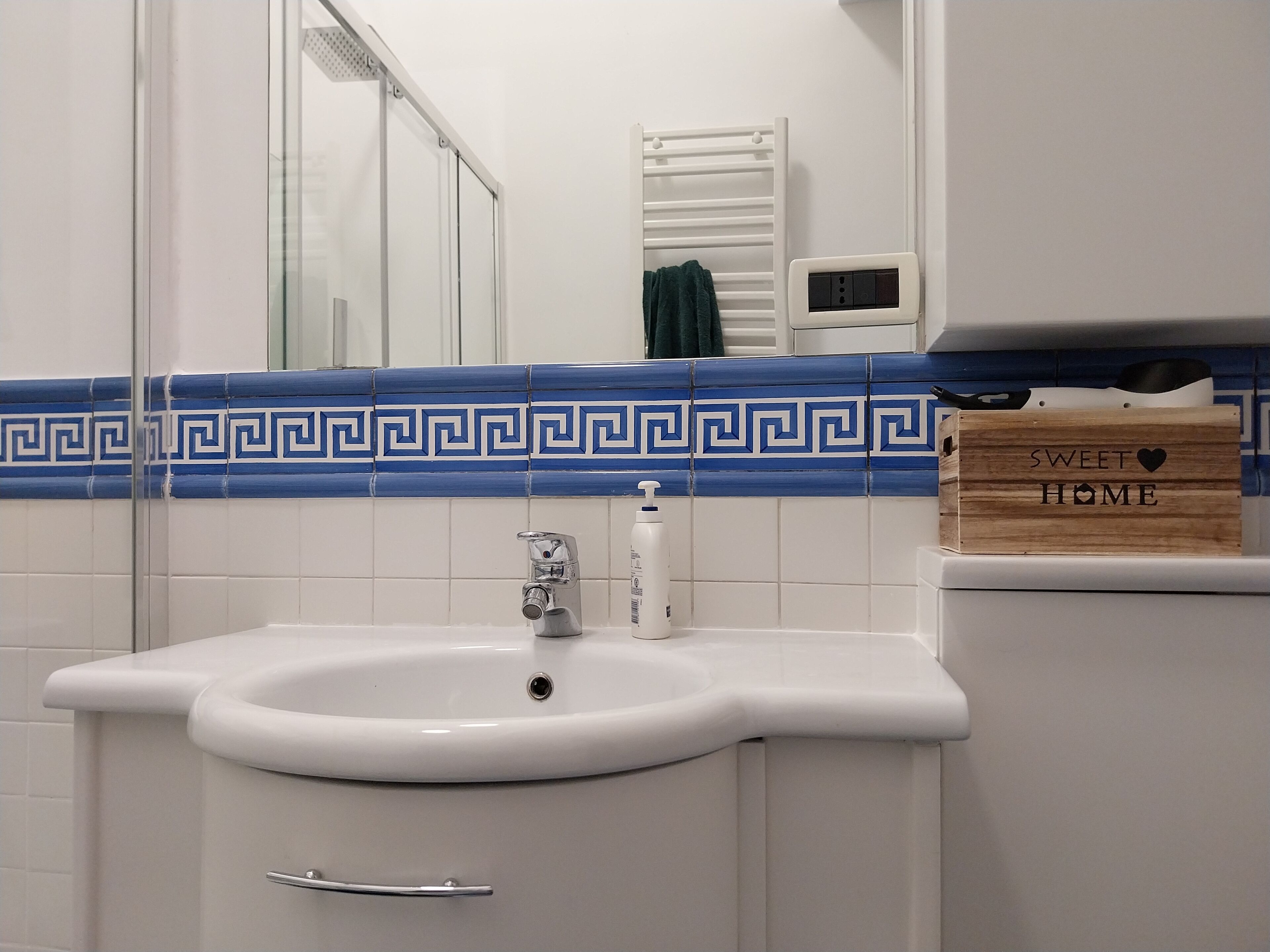 A bathroom with a white sink, a mirror, and a blue and white tiled backsplash.