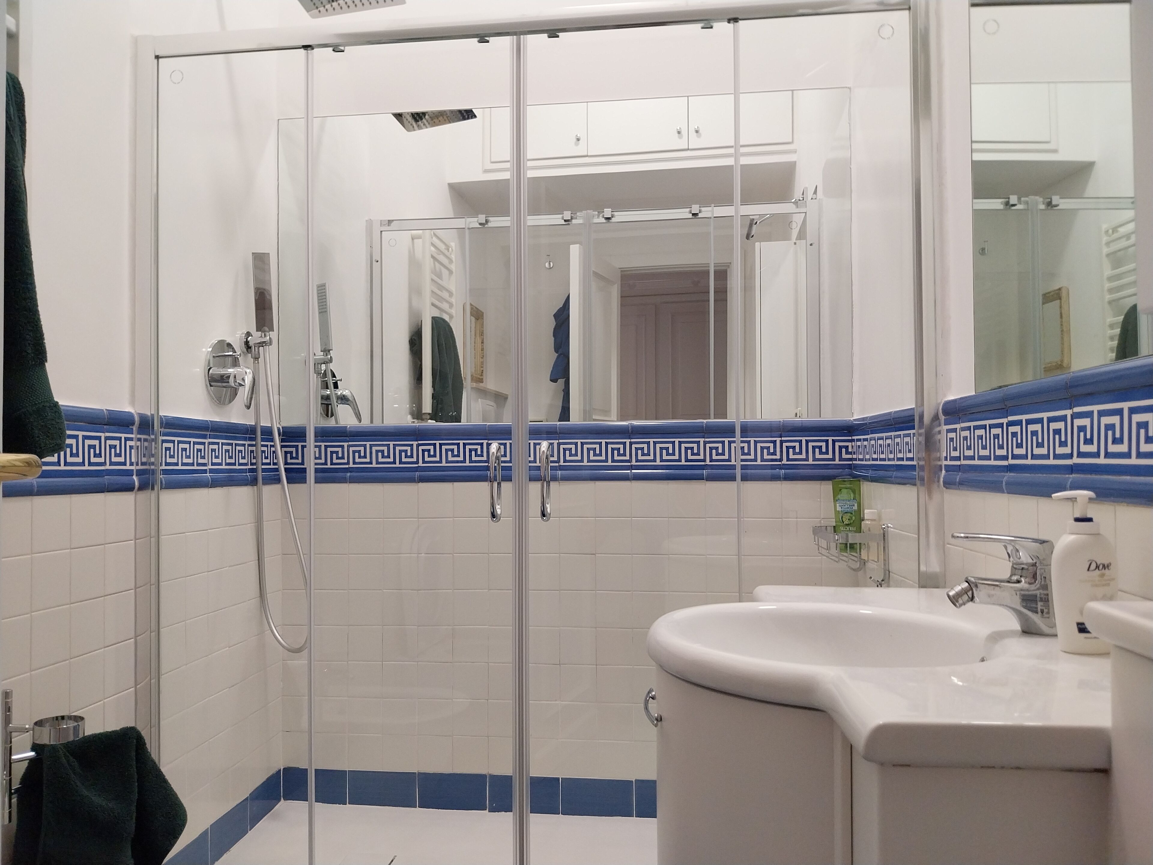 Een badkamer met een douchecabine van glas, een wastafel en een spiegel.