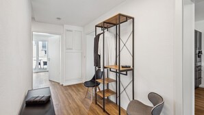 A modern room with a wooden floor, a desk with a laptop, a chair, a metal shelving unit, and a wardrobe. - Welcome to our stylish new construction vacation home in Dasing! (Dasing)