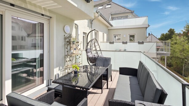 A balcony with a glass table and wicker chairs, a hanging chair, and a decorative metal shelf. - Welcome to our stylish new construction vacation home in Dasing! (Dasing)