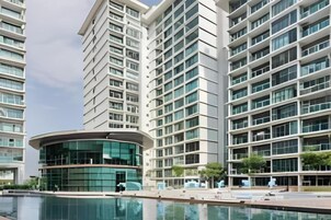 A modern high-rise building with a pool in front.