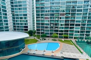 Un hotel moderno con area piscina, diversi piani e facciata in vetro.
