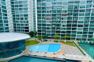 A modern hotel with a pool area, multiple floors, and a glass facade.