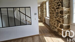 Eine Treppe führt zu einer oberen Etage, eine Steinmauer und ein Fenster mit Blick nach draußen.