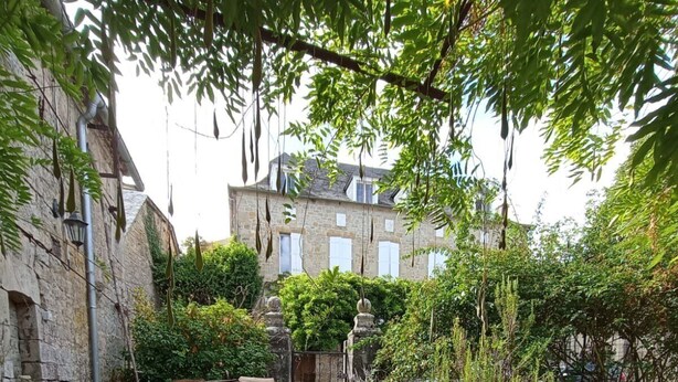 Zwei Schalen mit Feigen auf einer Steinfläche in einem Garten mit Steingebäuden und viel Grün im Hintergrund.