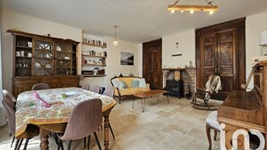 Ein geräumiges Wohnzimmer mit Esstisch, Stühlen, einer Couch, einem Kamin und einem Klavier.