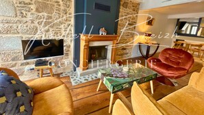 Una sala de estar acogedora con una pared de piedra, una chimenea, un televisor y asientos cómodos.