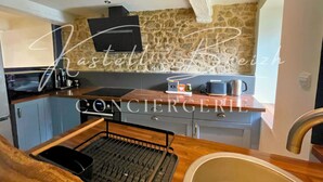Una cocina compacta con salpicadero de piedra, extractor de humos negro y encimera de madera.