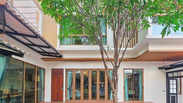 A modern house with a swimming pool, large glass doors, and a tree in the center. -  Serava Pet-Friendly Pool Villa Huahin (Hua Hin)