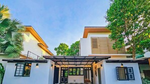 A modern two-story house with a covered entrance, a checkered driveway, and surrounding greenery. -  Serava Pet-Friendly Pool Villa Huahin (Hua Hin)
