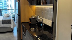 Et moderne køkken med indbygget ovn, vask og kaffemaskine. Der er et træskab og et vindue med udsigt over bybilledet.
