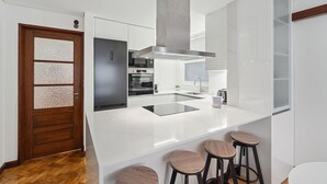 A modern kitchen with a large island, built-in oven, and a wooden door with frosted glass panels.