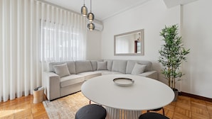 A modern living room with a sectional sofa, a round dining table, and a potted plant.