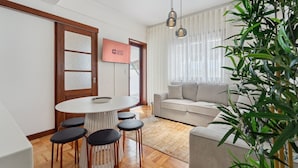 A modern living room with a round dining table, a sofa, and a large plant.