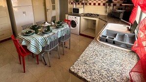 A compact kitchen with a dining area, equipped with a refrigerator, microwave, and gas stove. - A pleasant ground floor 5 minutes' walk from the beach (Hergla)