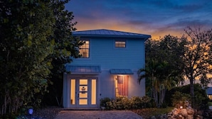 A two-story house with a front porch, a garage, and a driveway. - Movie Theater, Heated Pool, & Sauna - Luxe 4BR (West Palm Beach)