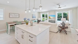 A spacious kitchen with a central island, pendant lighting, and a dining area with a table and chairs. - Movie Theater, Heated Pool, & Sauna - Luxe 4BR (West Palm Beach)