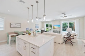 A spacious kitchen with a central island, pendant lighting, and a dining area with a table and chairs.