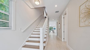 A staircase with white railings and wooden steps leading to a second floor. - Movie Theater, Heated Pool, & Sauna - Luxe 4BR (West Palm Beach)