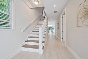 A staircase with white railings and wooden steps leading to a second floor. - Movie Theater, Heated Pool, & Sauna - Luxe 4BR (West Palm Beach)