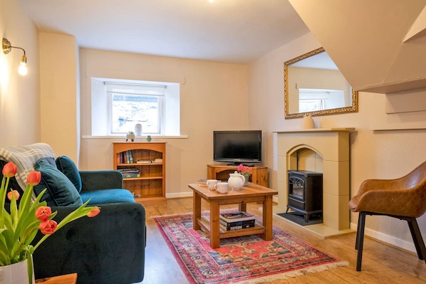 A cozy living room with a sofa, a coffee table, a fireplace, and a television.