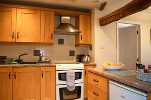 A kitchen with wooden cabinets, a stainless steel range hood, a stove, and a refrigerator.