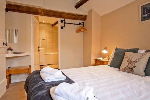 A bedroom with a bed, bedside table, lamp, and a wooden bench.