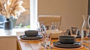 A neatly set dining table with plates, bowls, glasses, and cutlery. - Beech Cottage - Central Luxury (Derbyshire)