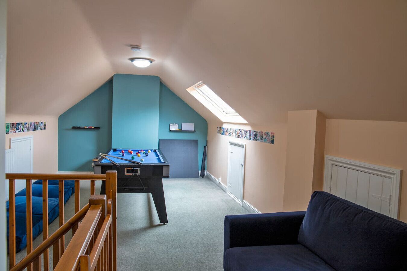 Ein Zimmer mit Billardtisch, einer Couch und einer Treppe, die zu einer anderen Ebene führt.