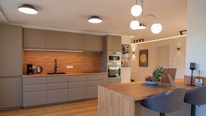 Una cocina moderna con armarios de madera, horno empotrado y una barra con taburetes.