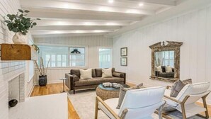 A spacious living room with a fireplace, a large mirror, and a cozy seating area. - A Little Gem - Ocean Views with Private Elevator (Jekyll Island)