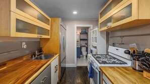 Una cucina compatta con mobili in legno, un lavandino in acciaio inossidabile, un fornello e un microonde.