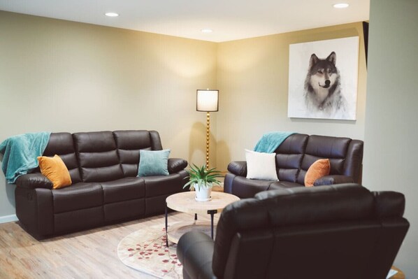 A living room with two leather sofas, a small round table, and a potted plant.