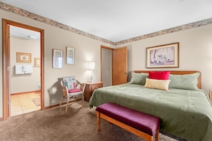 Bedroom with green bedding, an accent bench, and access to an adjoining bathroom. - Branson @ Pointe Royale Resort - Golf, Fish & Hike (Branson)