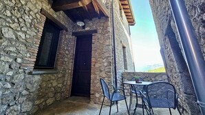 Un edificio de piedra con balcón de madera, una puerta y una mesa con sillas.