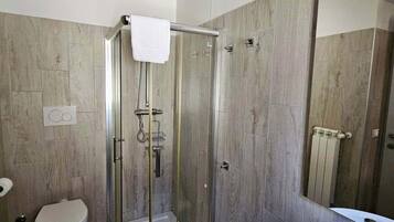 Ein modernes Badezimmer mit einer Duschkabine, Toilette, Bidet und Waschbecken mit Spiegel.