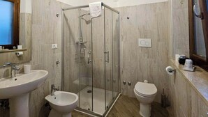Un baño moderno con ducha de vidrio, lavabo, bidé e inodoro.
