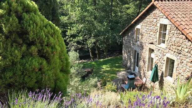 Una casa de piedra con jardín, con lavanda y césped bien cuidado.