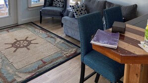 Una sala de estar acogedora con un sofá, dos sillones, una mesa de centro de madera y una alfombra estampada.