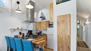 Una cocina moderna con armarios de madera, una isla central con sillas azules e iluminación colgante.