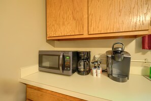 A kitchen with a microwave, coffee maker, and coffee pods on the counter. - Sheets Retreat | Hocking Hills, 80 Acres, Pond (New Plymouth)