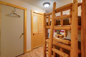 Une pièce avec une échelle en bois, un placard avec des portes coulissantes et un lit avec des oreillers.
